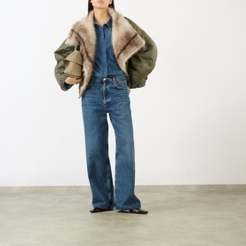 Model wearing The Frankie Shop Raw Wash denim shirt, styled with olive shearling bomber jacket and wide-leg blue jeans.