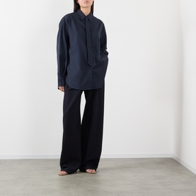 Model wearing The Frankie Shop navy oversized shirt with wide-leg trousers and strappy heeled sandals.