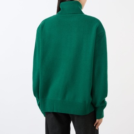 Model wearing The Frankie Shop Forest Green turtleneck jumper, back view, styled with black trousers.