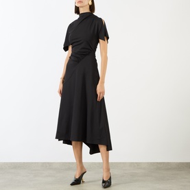 Model wearing Victoria Beckham black midi dress with draped high neck, short sleeves, and asymmetric flared skirt, styled with black heels.