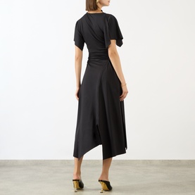 Model wearing Victoria Beckham black midi dress, rear view, ruched waist, asymmetric hem, short sleeves, styled with gold heeled mules.