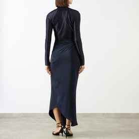 Model wearing Victoria Beckham Lea Gathered Wrap Dress in navy, showing gathered side detail, asymmetric hem, and subtle sheen finish. Styled with