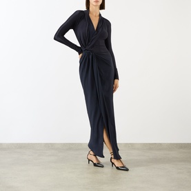 Model wearing Victoria Beckham Lea Gathered Wrap Dress in navy, draped V-neckline, long sleeves, gathered side detail, styled with black strappy heels