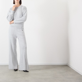Model wearing Victoria Beckham Grey Marl merino wool cashmere knit wide-leg trousers, styled with matching grey sweatshirt and black heels.