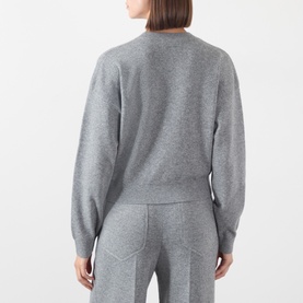 Model wearing Victoria Beckham mid grey marl merino wool cashmere blend crew neck sweater, styled with matching grey trousers, back view.