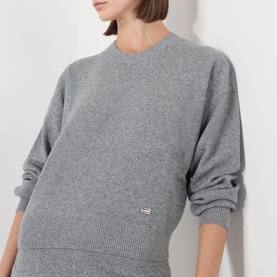 Model wearing Victoria Beckham mid grey marl merino wool cashmere crew neck knit sweatshirt, styled with matching grey knit trousers.