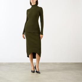 Model wearing Victoria Beckham Logo Rib-Knit Turtleneck Sweater in dark green, styled with a matching midi skirt and black heels