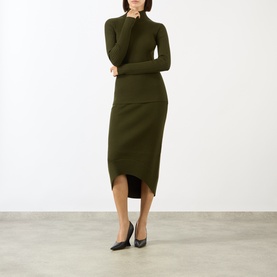 Model wearing Victoria Beckham Logo Rib-Knit Turtleneck Sweater in dark green, styled with matching knit midi skirt and black heels.