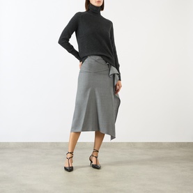 Model wearing Victoria Beckham Marie Turtleneck Sweater in dark grey wool, styled with a grey midi skirt and black heeled sandals.