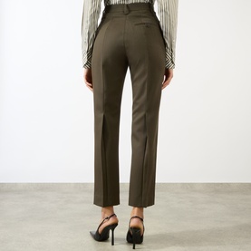 Model wearing Victoria Beckham Straight Leg Cropped Trousers in gold wool, high-rise with pressed creases, styled with black heels, rear view