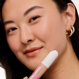 Model with Benefit Porefessional Concealer in shade 1C Ready held against cheek, gold hoop earring visible