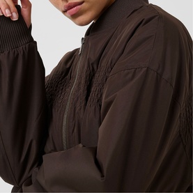 Model wearing Kaffe Arlette Cropped Bomber Jacket in Coffee Bean, showing ribbed cuffs and draped nylon panels at chest, close-up detail shot.