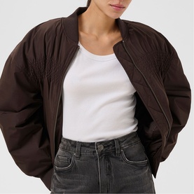 Model wearing Kaffe Arlette Cropped Bomber Jacket in Coffee Bean, draped lightweight style, styled with white top and grey jeans.