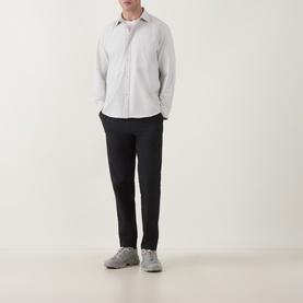 Model wearing Snow Peak ivory casual shirt with black tapered trousers and grey trainers, full-length view on white background.