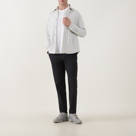 Model wearing Snow Peak ivory casual shirt with black slim-fit trousers and grey chunky trainers