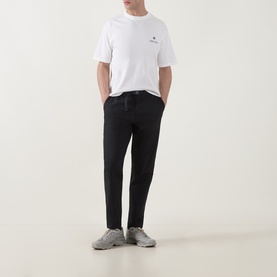 Model wearing Snow Peak off white T-shirt with small chest logo, styled with black tapered trousers and grey trainers.