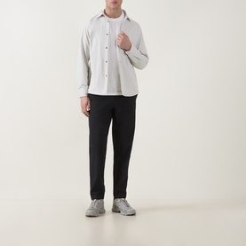 Model wearing Snow Peak off white long-sleeve shirt over white T-shirt, styled with black tapered trousers and grey trainers