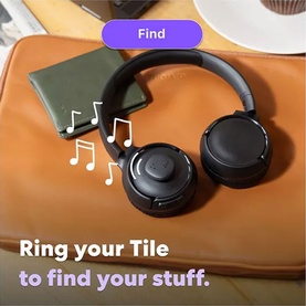 Black over-ear headphones resting on an orange leather bag beside a green wallet, with Tile app interface shown above