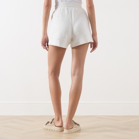 Model wearing Varley Ivory Marl shorts, back view, with espadrille sandals visible.