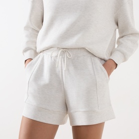 Model wearing Varley Ivory Marl shorts with drawstring waist and cuffed hem, styled with a matching ivory sweatshirt.