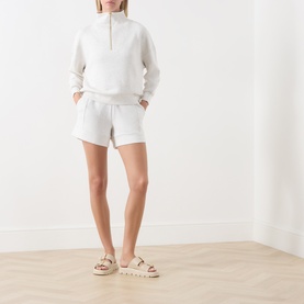Model wearing Varley Ivory Marl shorts with matching half-zip sweatshirt and beige chain-strap sandals.