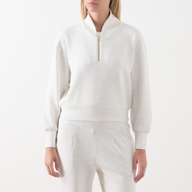 Model wearing Varley Ivory Marl half-zip sweatshirt with gold zip, styled with matching wide-leg joggers