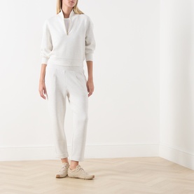 Model wearing Varley Ivory Marl sweat joggers styled with a matching half-zip sweatshirt and beige trainers.