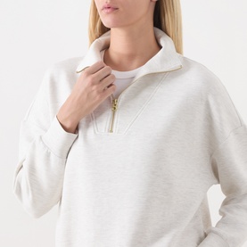 Model wearing Varley Ivory Marl sweat with gold quarter-zip fastening and ribbed collar, close-up detail shot.