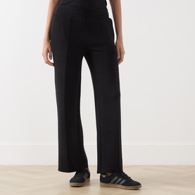 Model wearing Varley black wide-leg sweat trousers, styled with grey Adidas Gazelle trainers, cropped view from waist down.