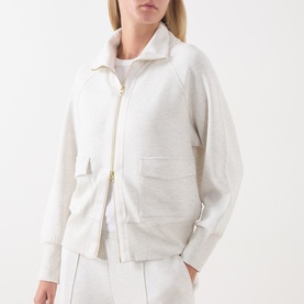 Model wearing Varley Ivory Marl zip-up sweat jacket with gold zip, raglan sleeves and front patch pockets, styled with white trousers.