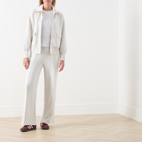 Model wearing Varley Ivory Marl sweat jacket and wide-leg trousers, styled with a white tee and burgundy trainers.