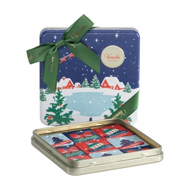 Venchi Christmas chocolate gift tin with winter village scene, green ribbon bow, open lid showing assorted chocolates inside