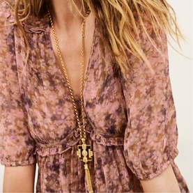 Model wearing Bash pink floral chiffon mini dress with V-neckline, styled with a long gold chain pendant necklace.