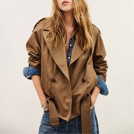 Model wearing Bash brown double-breasted cropped trench jacket with belt, styled with denim shirt and jeans