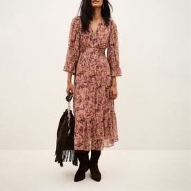 Model wearing Bash pink floral midi dress with V-neck and flared sleeves, styled with black ankle boots and fringed bag