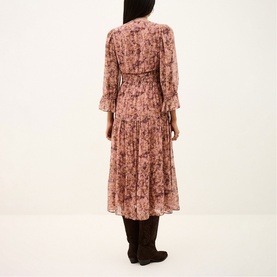 Model wearing Bash pink floral print midi dress with long sleeves and tiered skirt, styled with dark knee-high boots