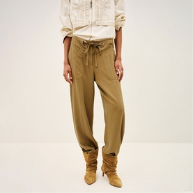 Model wearing Bash yellow relaxed-fit tapered trousers with drawstring waist, styled with cream top and tan suede boots