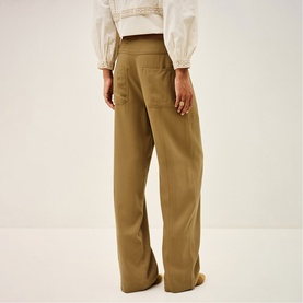 Model wearing Bash yellow wide-leg trousers, rear view, styled with a white cropped top