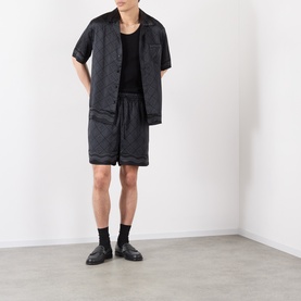 Model wearing Casablanca black silk shorts with matching short-sleeve shirt, black vest, socks and loafers.