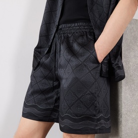 Model wearing Casablanca black silk shorts with tonal geometric jacquard pattern, elasticated waist and side pockets, styled with matching jacket
