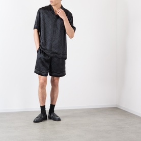 Model wearing Casablanca black silk shorts with matching black short-sleeve shirt, black socks and black loafers.