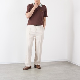 Model wearing Casablanca brown cotton polo with embroidered detail, styled with cream wide-leg trousers and brown loafers
