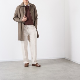 Model wearing Casablanca brown cotton polo, styled with taupe overcoat, cream trousers, and brown leather loafers.