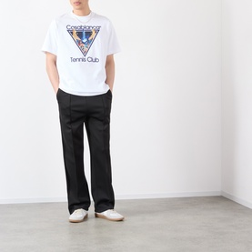 Model wearing white Casablanca Tennis Club graphic T-shirt with black wide-leg trousers and white slip-on shoes