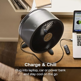 Dimplex black desktop circulation fan on a wooden desk beside a laptop and remote control, with "Charge & Chill" text overlay