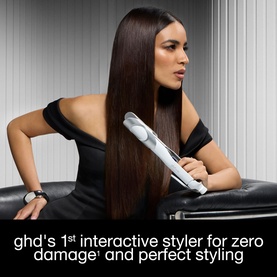 Model with GHD hair straightener styled into sleek straight brunette hair, wearing black off-shoulder top. Text overlay promotes zero damage styling.