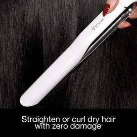 GHD hair straightener in white, shown gliding through dark hair with text: Straighten or curl dry hair with zero damage