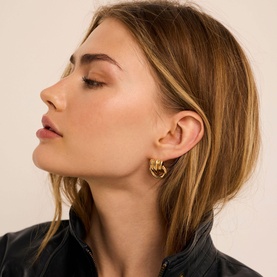 Model with Mint Velvet gold hoop earrings featuring knot detail, styled with a dark jacket