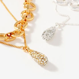 Mint Velvet gold-tone chain necklace with crystal-encrusted teardrop pendant, shown alongside a silver-tone version