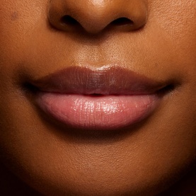 Model wearing a glossy nude-brown lip colour, close-up shot showing natural-looking finish on deep skin tone